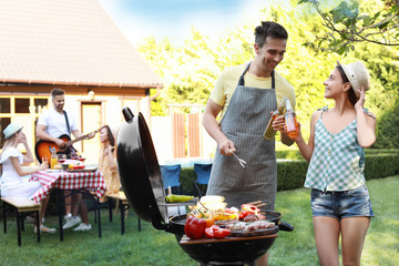 Poster - Young man and woman near barbecue grill outdoors