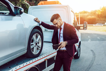 Wall Mural - Elegant middle age business man calling towing service for help on the road. Roadside assistance concept.