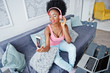 © AS Photo Family - Photo of screen mobile phone young african american woman sitting on the couch, listen music on earphones.