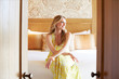 © Trinette Reed/Stocksy - Portrait of beautiful woman sitting on a bed at a luxury resort