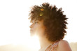© Trinette Reed/Stocksy - Portrait of African American woman backlit by the sun at the beach