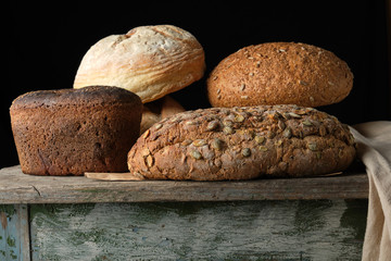 whole various baked rye flour bread rolls on an old wooden table