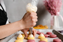 Crop Hand Squeezing Cream On Macarons