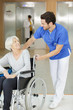 side view of social worker pushing wheelchair with senior woman