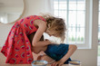 © Cavan Images - Brother and sister hugging and playing at the table whilst eating