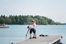 Two Kids Fishing On A Jetty By The Sea