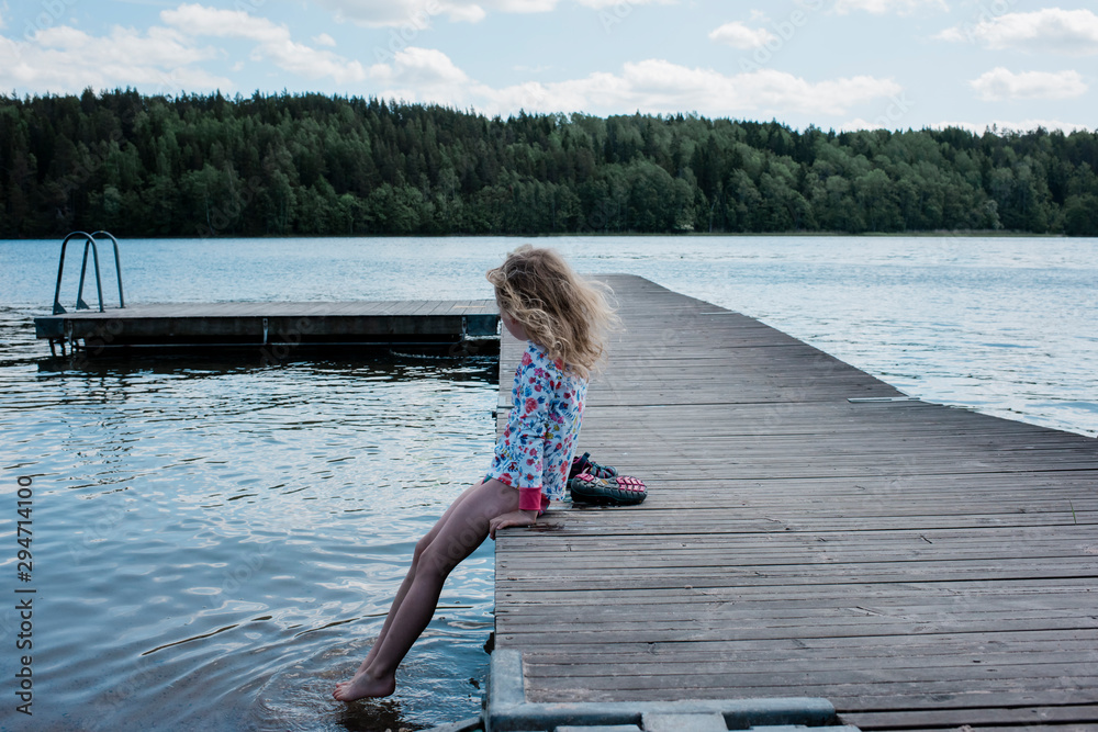 Young girl sitting on a jetty looking at the water Stock Photo | Adobe ...