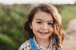 © Cavan Images - Portrait of young school-aged girl with brown eyes smiling at camera