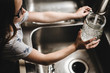 © Cavan Images - Little girl fills vase with water at kitchen sink