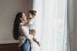 © Cavan Images - Side view of mother and toddler son playing in natural light studio
