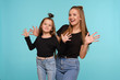 © nazarovsergey - Mom and daughter with a funny hairstyles, dressed in black shirts and blue denim jeans are posing against a blue studio background. Close-up shot.
