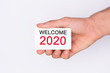 © Adga - Welcome 2020 . Hand holding a white card . White background. Copy space