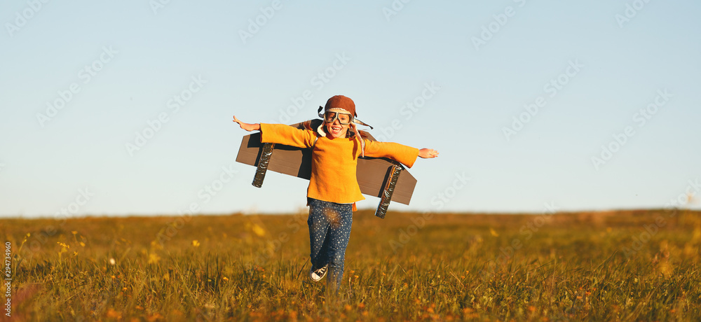 Child pilot aviator with wings of airplane dreams of traveling in summer  at sunset. - obrazy, fototapety, plakaty 