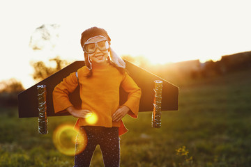 Wall Mural - Child pilot aviator with wings of airplane dreams of traveling in summer  at sunset.