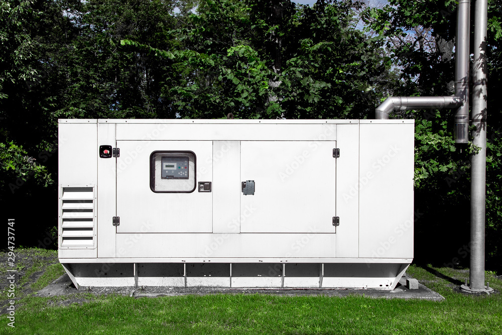 backup diesel electric power emergency generator mounted on a green lawn with green trees and a separate exhaust pipe for environmental safety. - obrazy, fototapety, plakaty 
