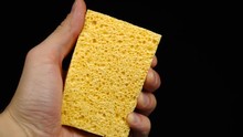 Showing A Yellow Sponge For Dishwashing On A Black Background
