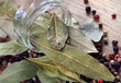 dry bay leaf in a glass jar on a wooden table. bay leaf and pepper mixture close up