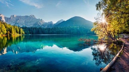 colorful summer view of fusine lake. bright morning scene of julian alps with mangart peak on backgr