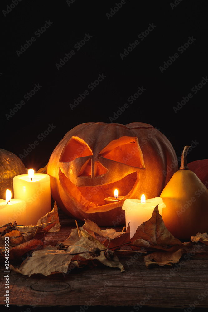 dry foliage, burning candles and Halloween carved pumpkin on wooden rustic table isolated on black - obrazy, fototapety, plakaty 
