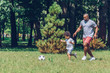 © LIGHTFIELD STUDIOS - cheerful african american father and son playing football in park