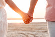 © Drobot Dean - Close up of a couple holding hands at the beach