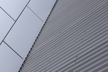 Angular view of corner of building - junction of grey smooth tiled wall and metal corrugated wall