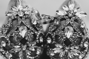 Modern wedding jewelry. Closeup of two wedding rings and engagement ring on female leather shoes.