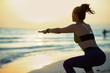 healthy woman on seashore at sunset doing squats