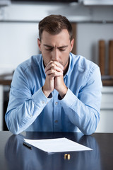 Wall Mural - sad man in shirt sitting at table with ring and divorce documents