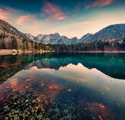 Great morning view of Fusine lake. Colorful autumn sunrise in Julian Alps with Mangart peak on background, Province of Udine, Italy, Europe. Beauty of nature concept background.