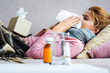selective focus of attractive and ill woman sneezing and using napkin