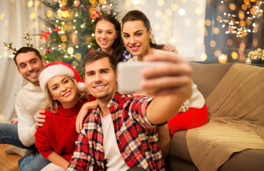 Sticker - celebration and holidays concept - happy friends with glasses celebrating christmas at home party and taking selfie by smartphone