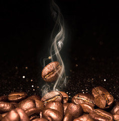 Roasted coffee beans. Seeds of freshly roasted coffee with smoke. Coffee beans closeup with emphasis on the grain with smoke.