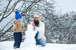 © Volodymyr - Winter background with snowflakes and snowman. Father and son making snowman in the snow. Handmade funny snow man. Best winter game for happy family.