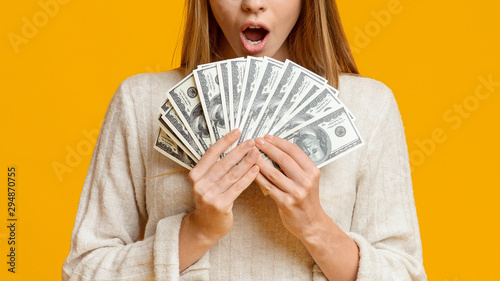 Fotografía Amazed young woman holding bunch of money banknotes, celebrating profit