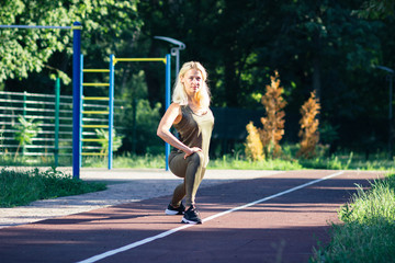  Beautiful young woman makes sport exercises on the sport ground, blurred background