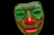 Spooky Clown Mask Isolated On Black With Red Nose, Lips And Glowing Eyes.
