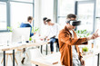 © LIGHTFIELD STUDIOS - young businessman using vr headset and touching something with finger while multicultural colleagues working in office