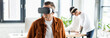 © LIGHTFIELD STUDIOS - panoramic shot of young businessman using vr headset while multicultural colleagues working in office