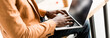 © LIGHTFIELD STUDIOS - cropped view of african american businessman sitting on desk and using laptop, panoramic shot
