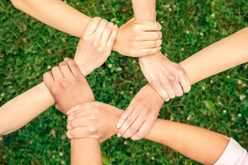 Volunteering. Young people volunteers outdoors together holding hands unity top view close-up