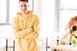 © LIGHTFIELD STUDIOS - cheerful young businessman smiling at camera while standing with crossed arms in office