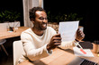 © LIGHTFIELD STUDIOS - happy african american businessman looking at paper while working at night in office
