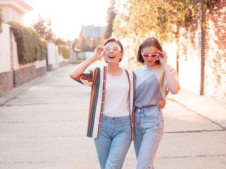 Wall Mural - Two fashionable young women walking down the street