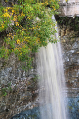 Wall Mural - large waterfall with high cliffs and trees with autumn foliage