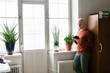 © FOLIO - Senior man using smart phone by window