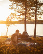 © FOLIO - Young woman reading at sunset by Lake Norra Bredsjon, Sweden