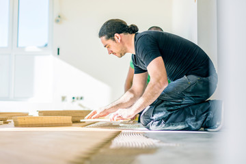 Wall Mural - Carpenter on work putting wood parquet pieces. Home construction 