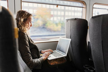 Young woman commuter on train using laptop