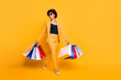 Full size photo of positive cheerful girl have leisure time feel dream dreamy hold bags go from shopping center wear style blazer trousers stilettos isolated over yellow color background